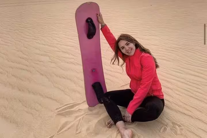 Traveler sandboarding on dunes in Bahariya Oasis desert, adventure on 3 Days Eco camping tour Egypt