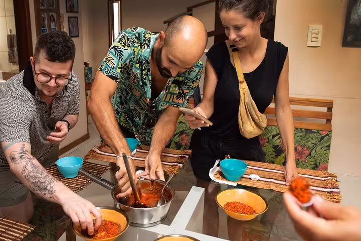 Guests engaging in a lively Bahian cooking class, mixing spices and capturing moments in Salvador.