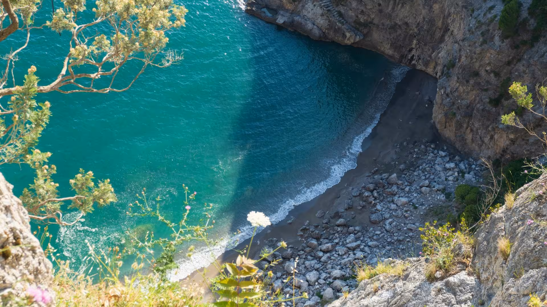 Aerial view of a secluded cove with turquoise waters and rocky beach in Baia Infreschi, ideal for a boat excursion.