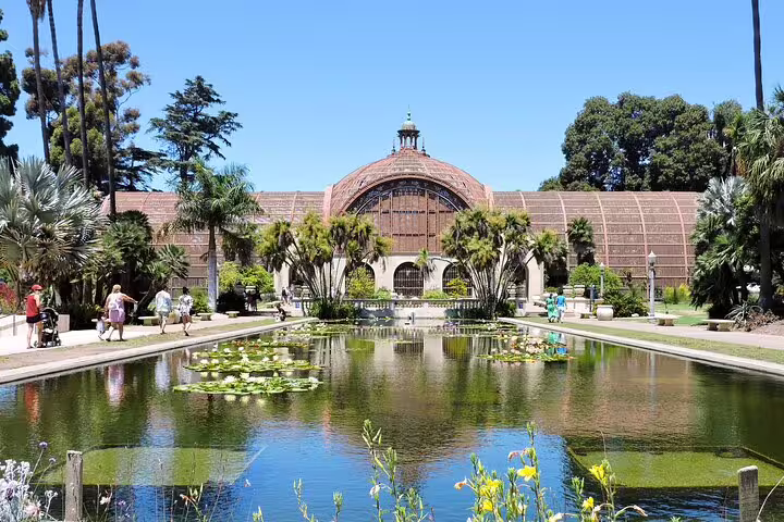 Balboa Park Botanical Building with lily pond reflecting ornate domed greenhouse surrounded by palm trees, San Diego