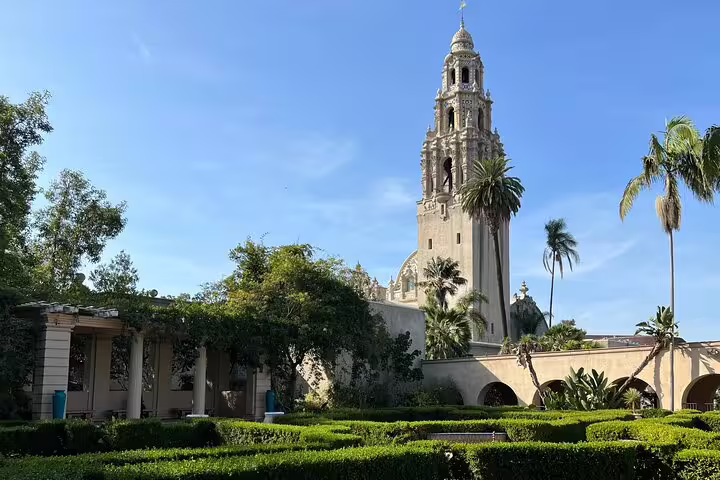 California Tower and lush garden hedges at Balboa Park, San Diego, with palm trees and blue sky