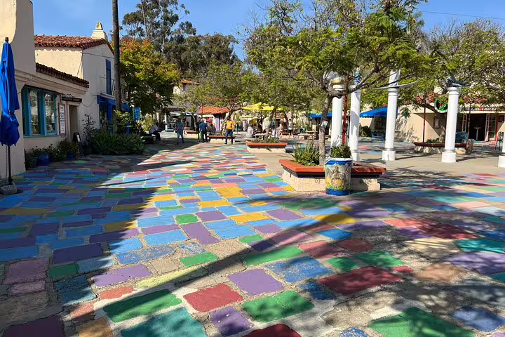 Colorful mosaic tile plaza at Balboa Park San Diego with trees and Spanish-style buildings