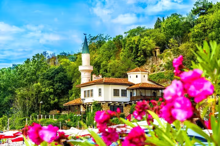 Picturesque Balchik Palace with a distinctive turret nestled amid vibrant flowers and lush greenery.