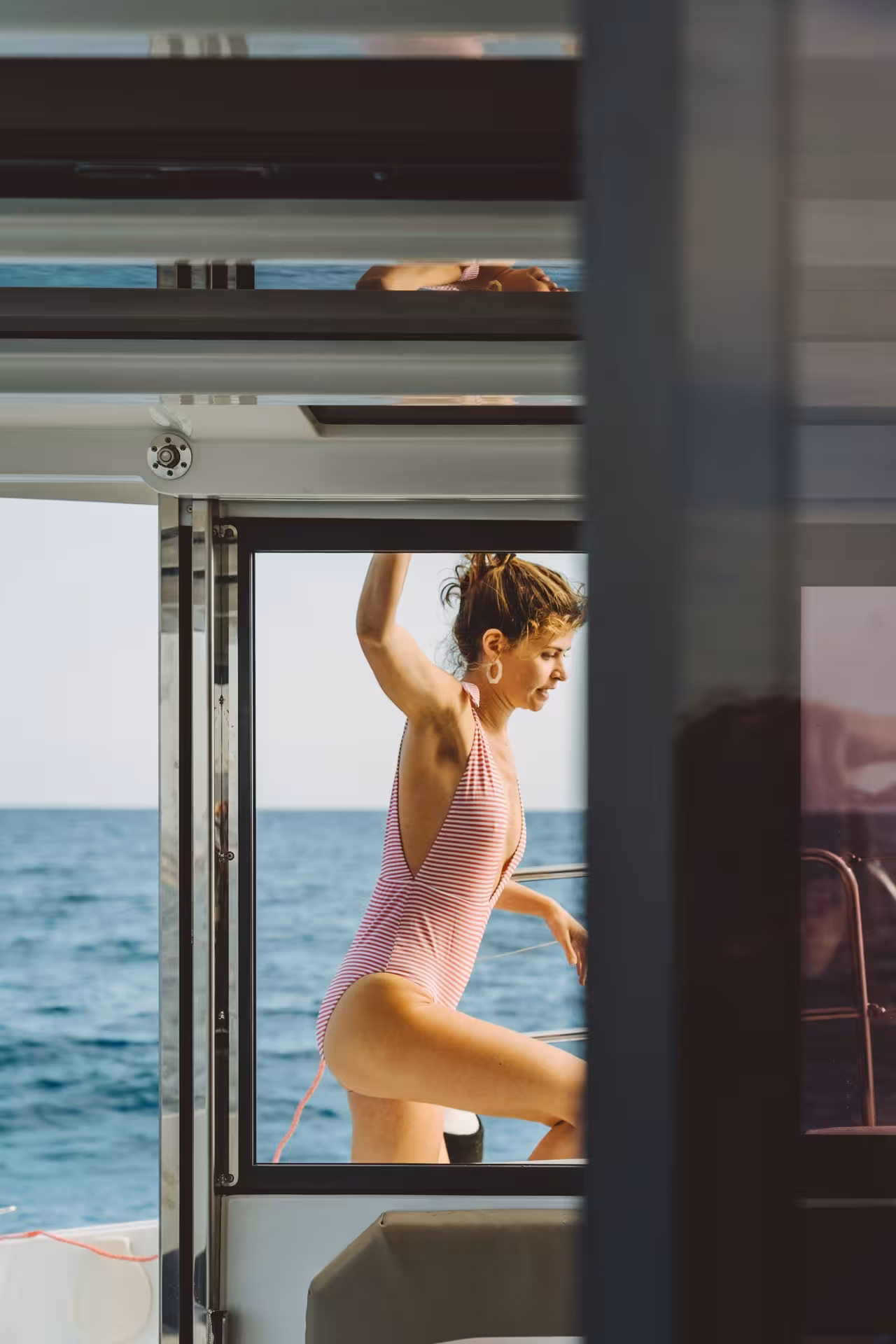 Guest in striped swimsuit stepping through cabin door on Bali 4.1 luxury catamaran cruise in Barcelona