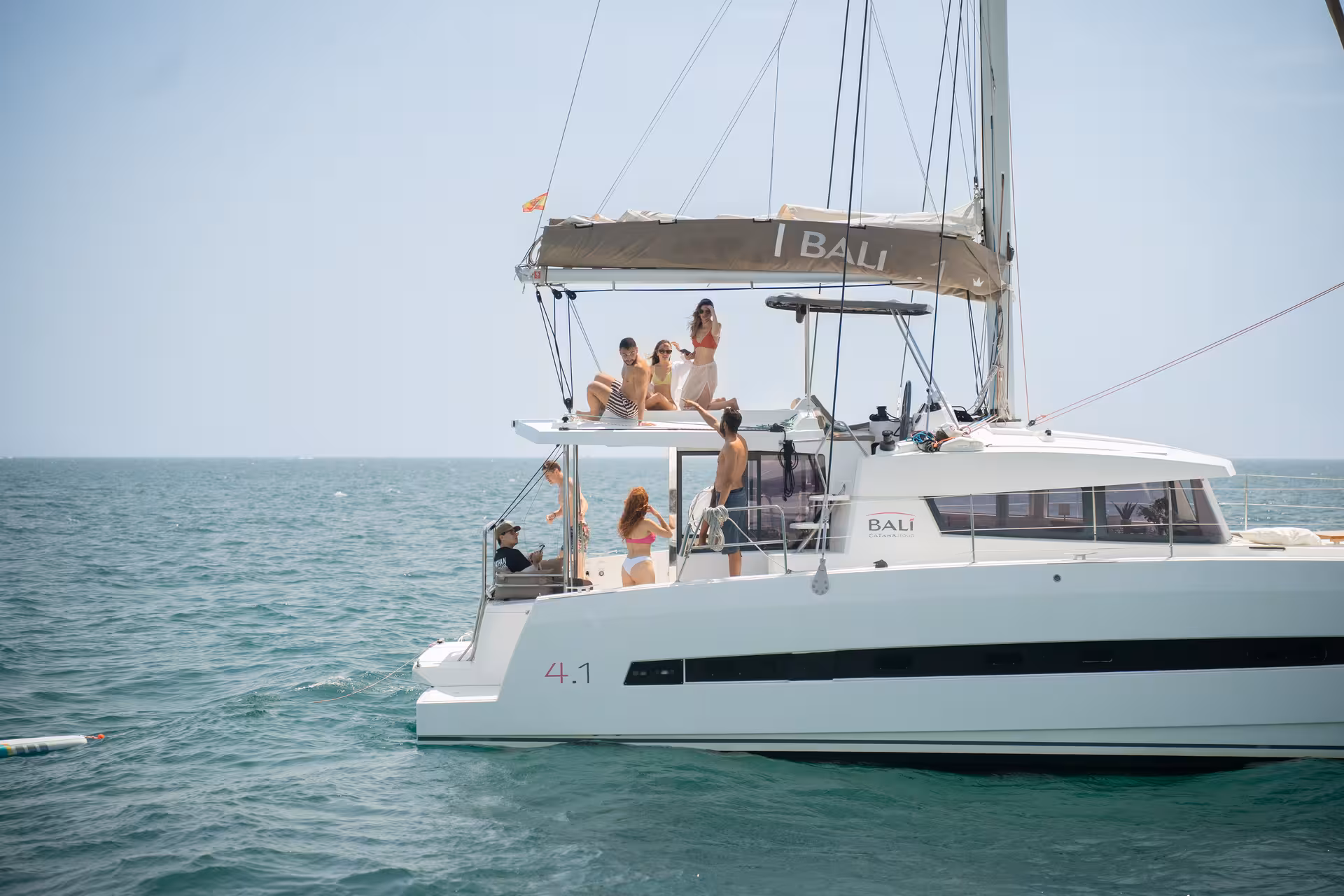 Bali 4.1 luxury catamaran sailing off Barcelona with guests sunbathing on deck on a 4-hour private cruise