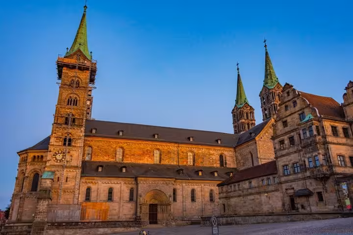 Bamberg Cathedral with four green spires and Romanesque architecture glowing at dusk, Germany