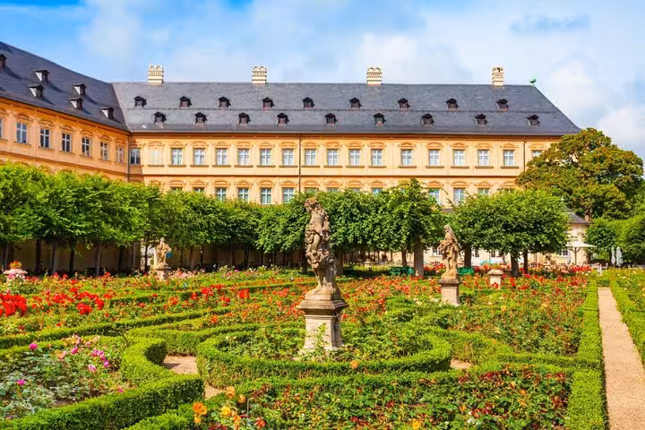 Baroque rose garden with sculpted hedges and statues in front of the Bamberg New Residence palace