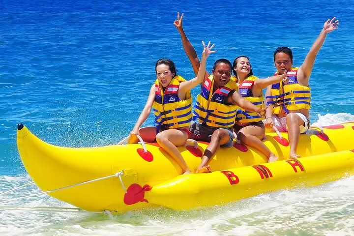 Friends riding banana boat in the Red Sea at Orange Bay, Hurghada VIP snorkeling day trip fun