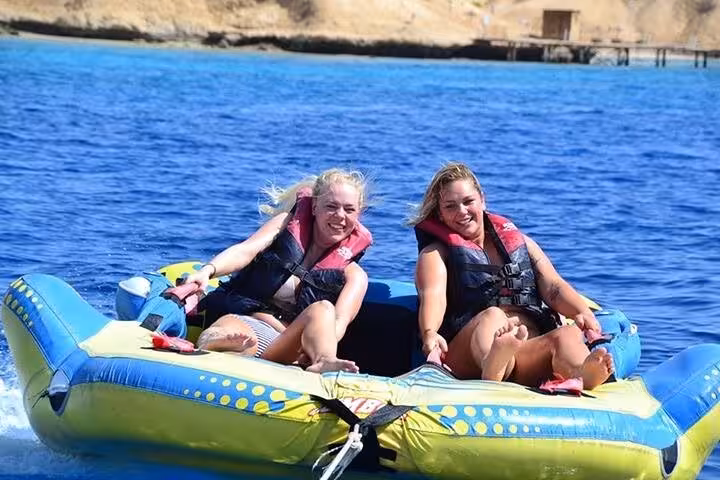 Two women riding a banana boat on the Red Sea during Giftun Island trip from Hurghada with water sports