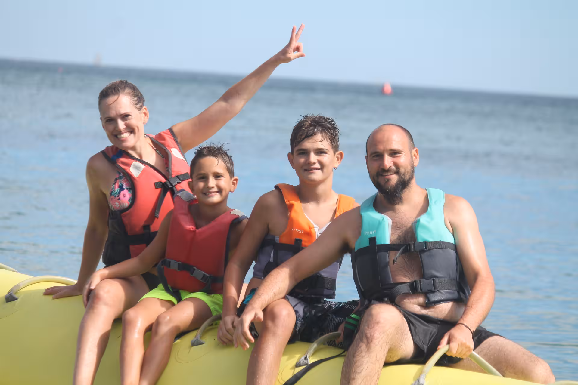Happy family wearing life jackets sitting on a yellow banana boat in Armacao de Pera during a fun family boat tour