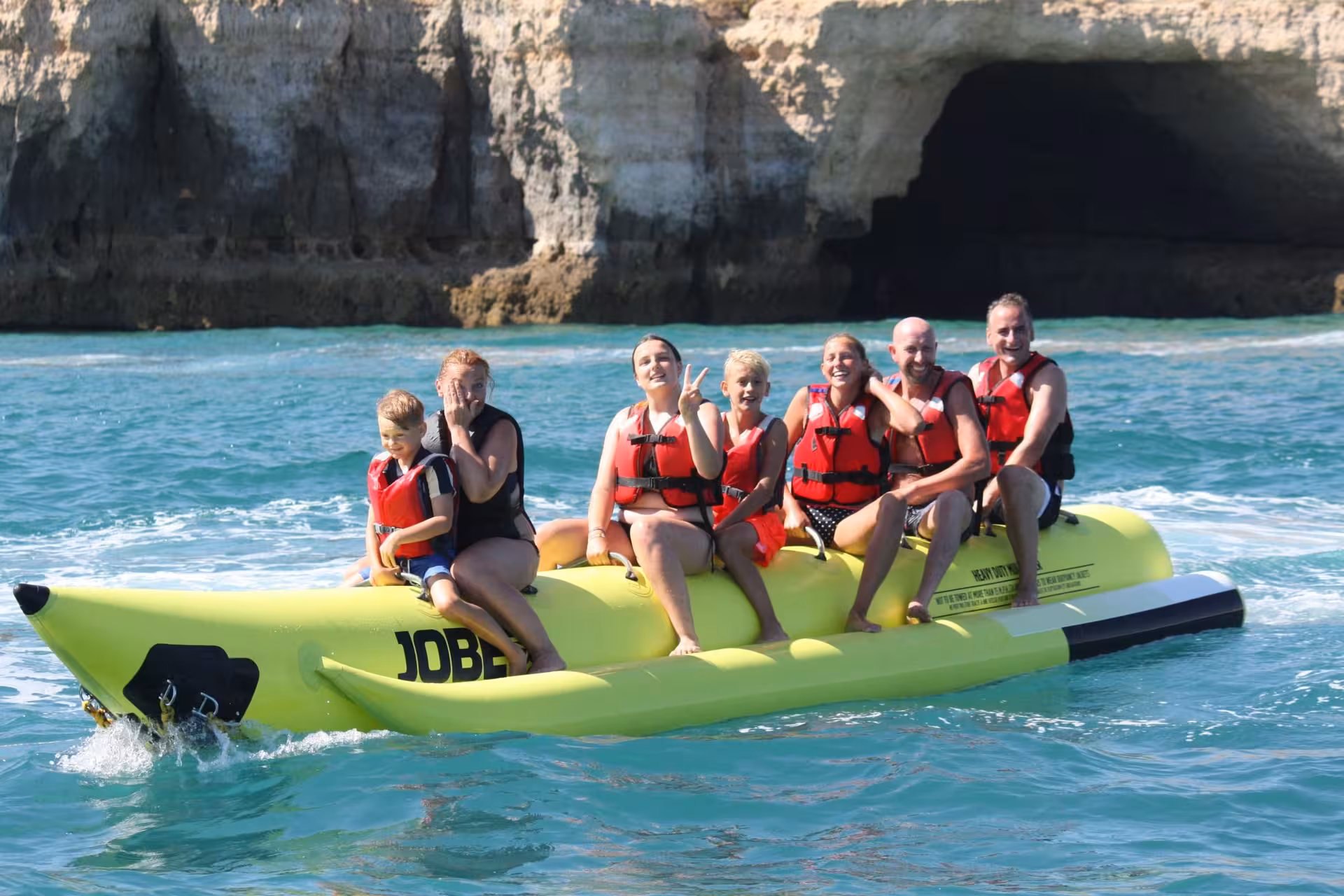 Family enjoying a thrilling banana boat ride near scenic sea caves in Armacao de Pera Algarve Portugal