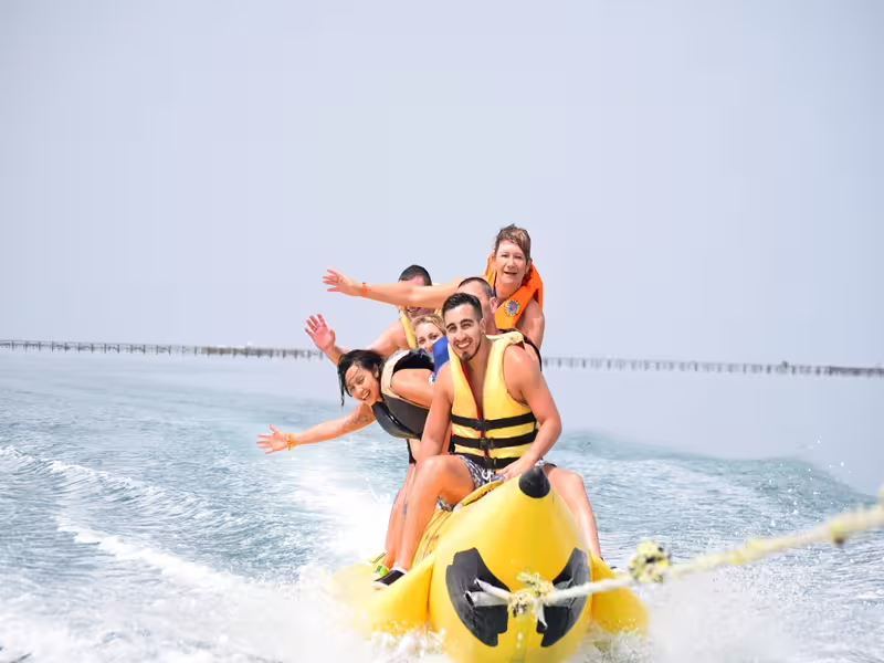 Group riding a banana boat in Sharm El Sheikh, Red Sea water sports adventure day out with life jackets
