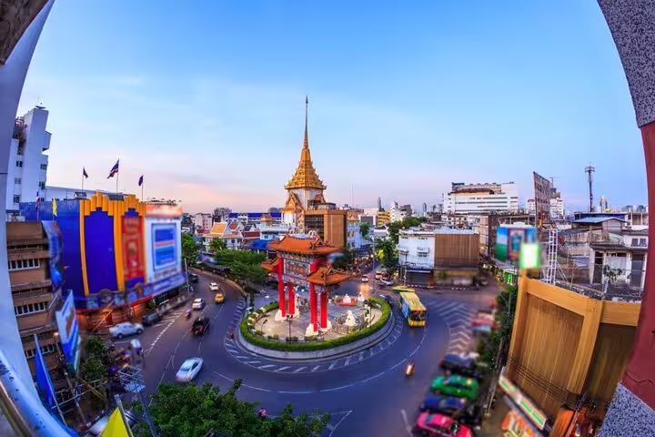 Aerial fisheye view of Bangkok Chinatown gate roundabout with golden temple spire at dusk