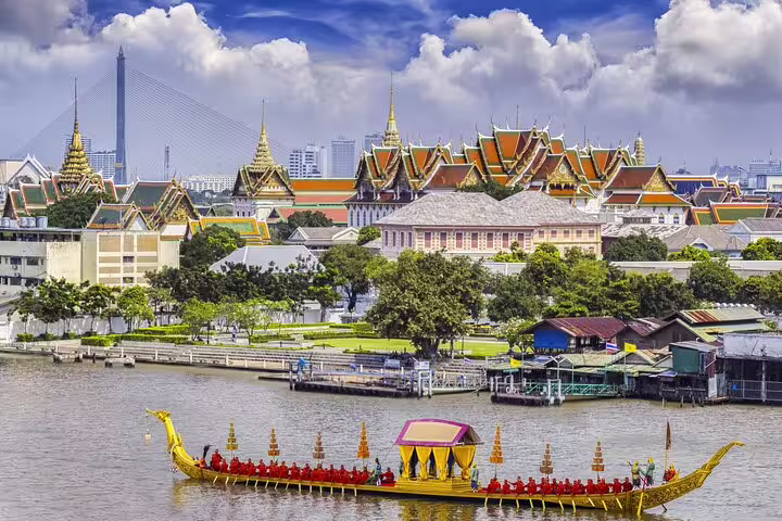 Royal Barge on Chao Phraya River with Bangkok Grand Palace and golden temple spires in background