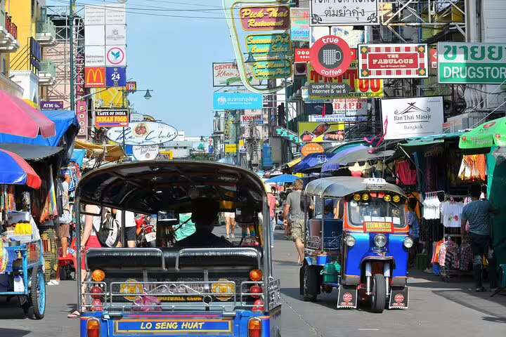 Colorful tuk-tuks on busy Khao San Road in Bangkok old town with vibrant market stalls and signs