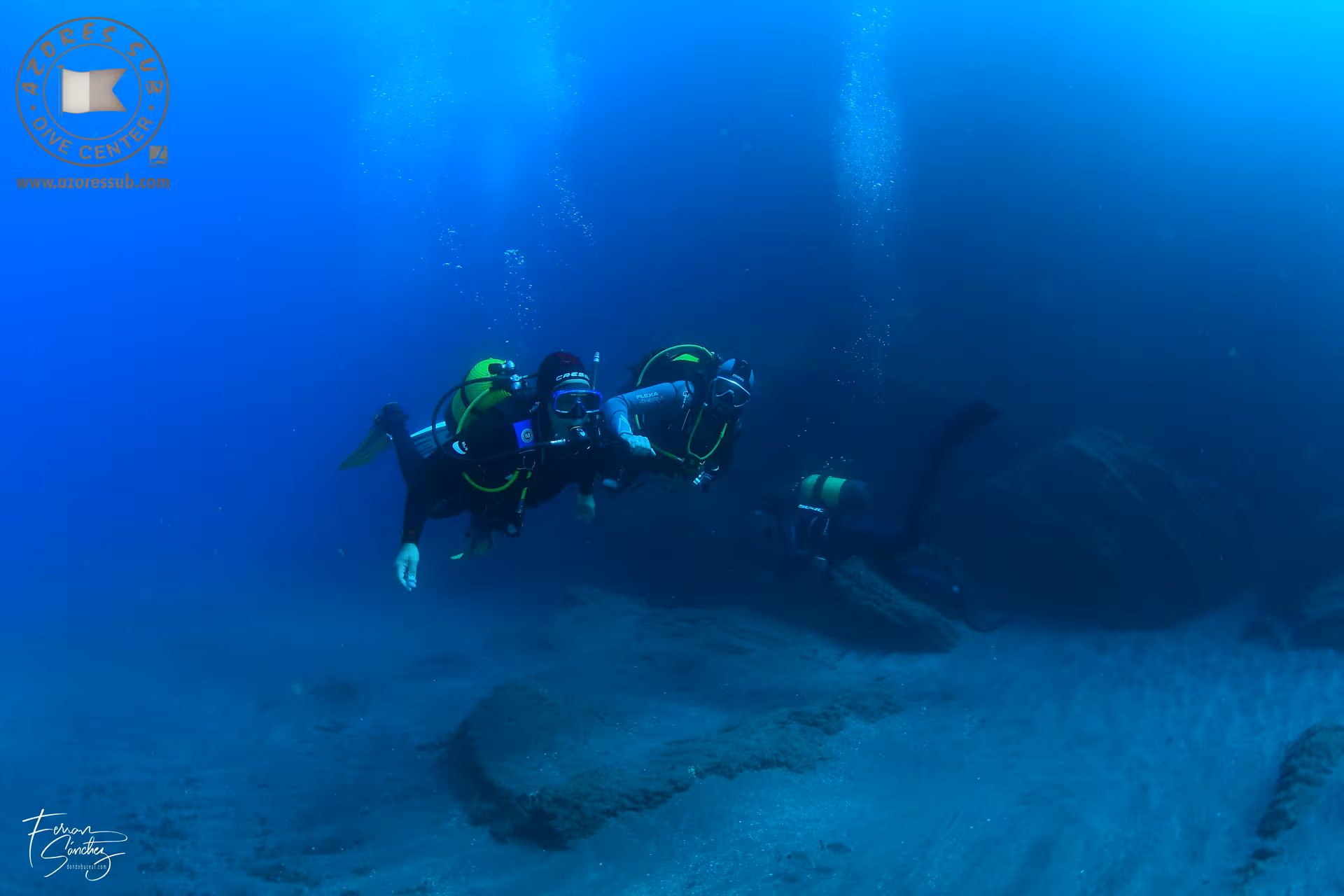 Two scuba divers exploring deep blue seascape on Baptism at Sea introductory dive tour with certified guide