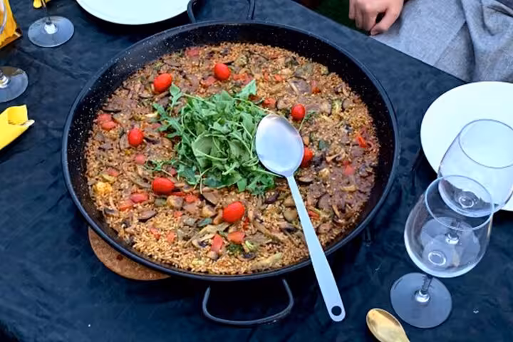 Large pan of authentic Spanish paella with fresh arugula and cherry tomatoes, ready for tasting in Barcelona.