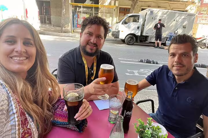 Tourists enjoying drinks at an outdoor cafe on a sunny day in Barcelona, showcasing local culture and gastronomy.