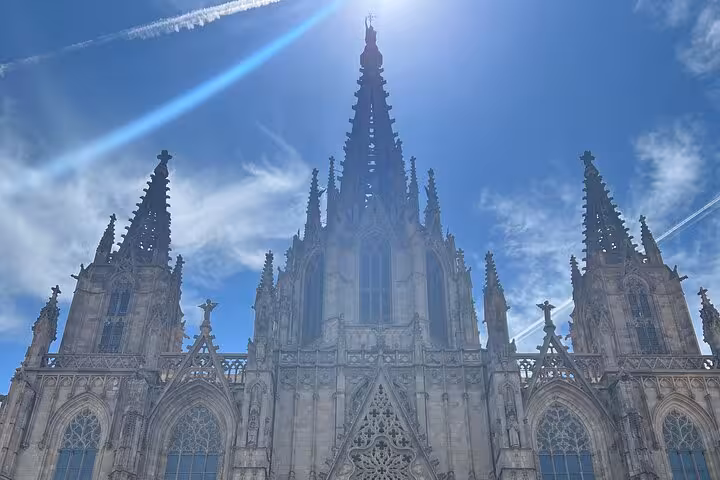 Gothic architecture of Barcelona Cathedral against a clear blue sky on guided city tour by local transport.