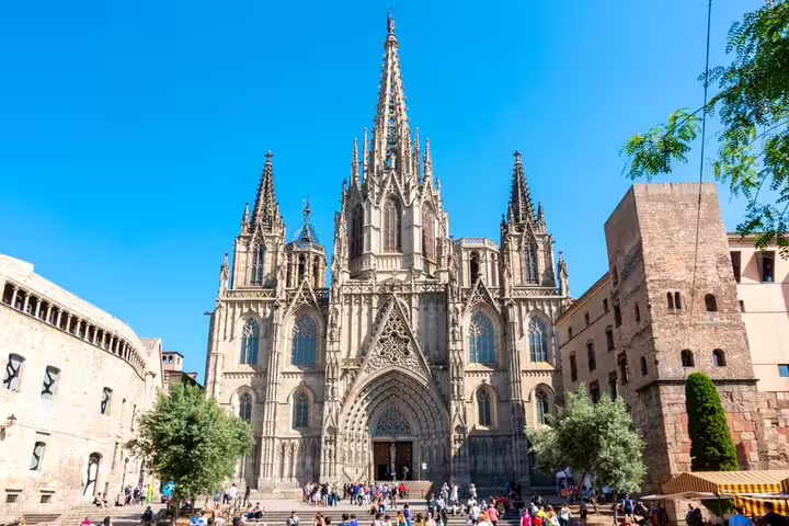 Gothic facade of Barcelona Cathedral with ornate spires and tourists in the plaza below