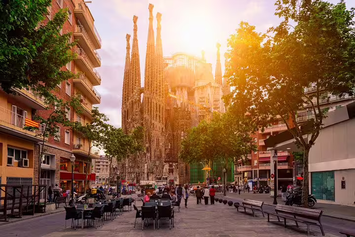 Sagrada Familia basilica towering over Barcelona street with outdoor café seating at golden hour