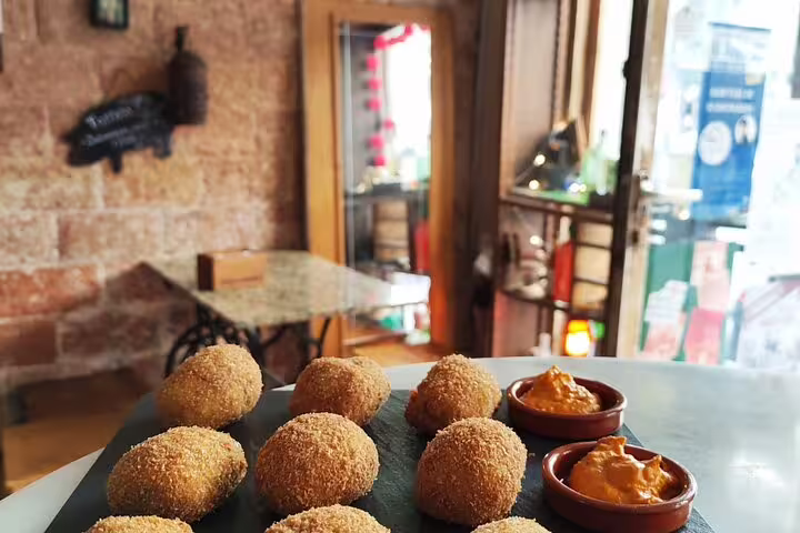 Golden croquettes served with spicy sauce on a table in a cozy Barcelona eatery.