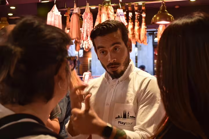 Tour guide explaining local cuisine in a vibrant Barcelona market during a cultural walking tour.