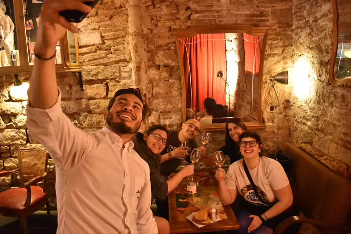 Group of friends toasting wine and taking a selfie in a cozy Barcelona restaurant on a cultural tour.