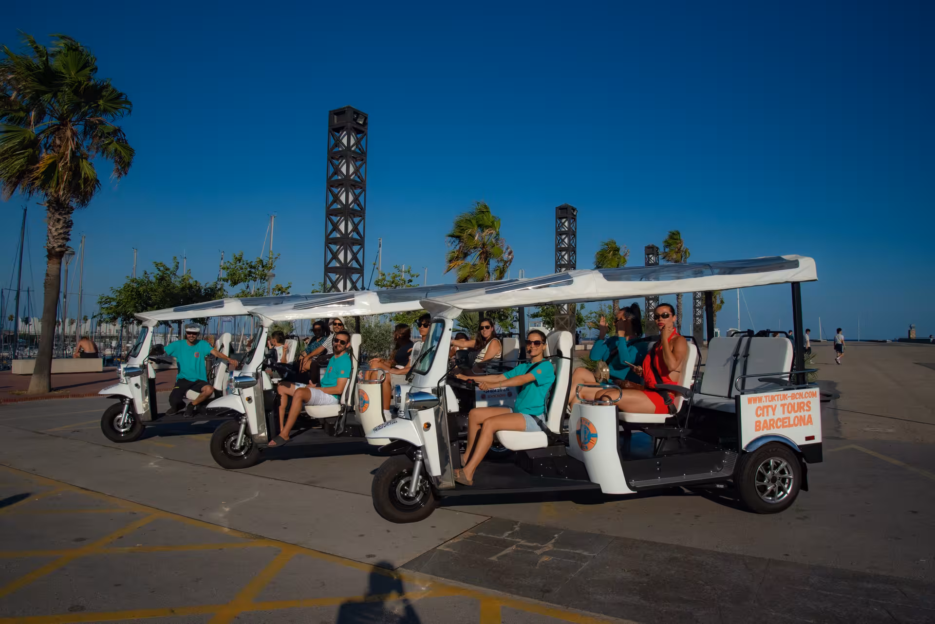 Fleet of electric tuk tuks at Barcelona Port Vell marina, ready for a Regular city sightseeing tour by the sea