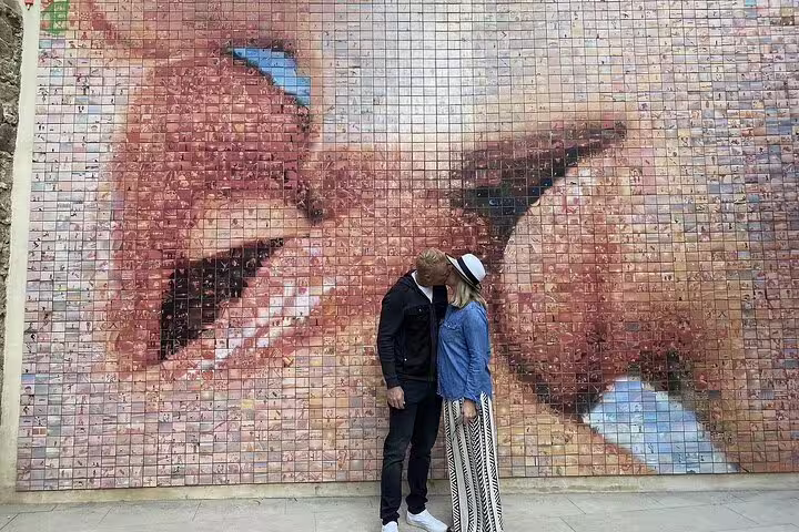 Couple poses in front of a colorful mosaic wall on a Barcelona VIP Private Tour of Sagrada Familia and Park Güell.