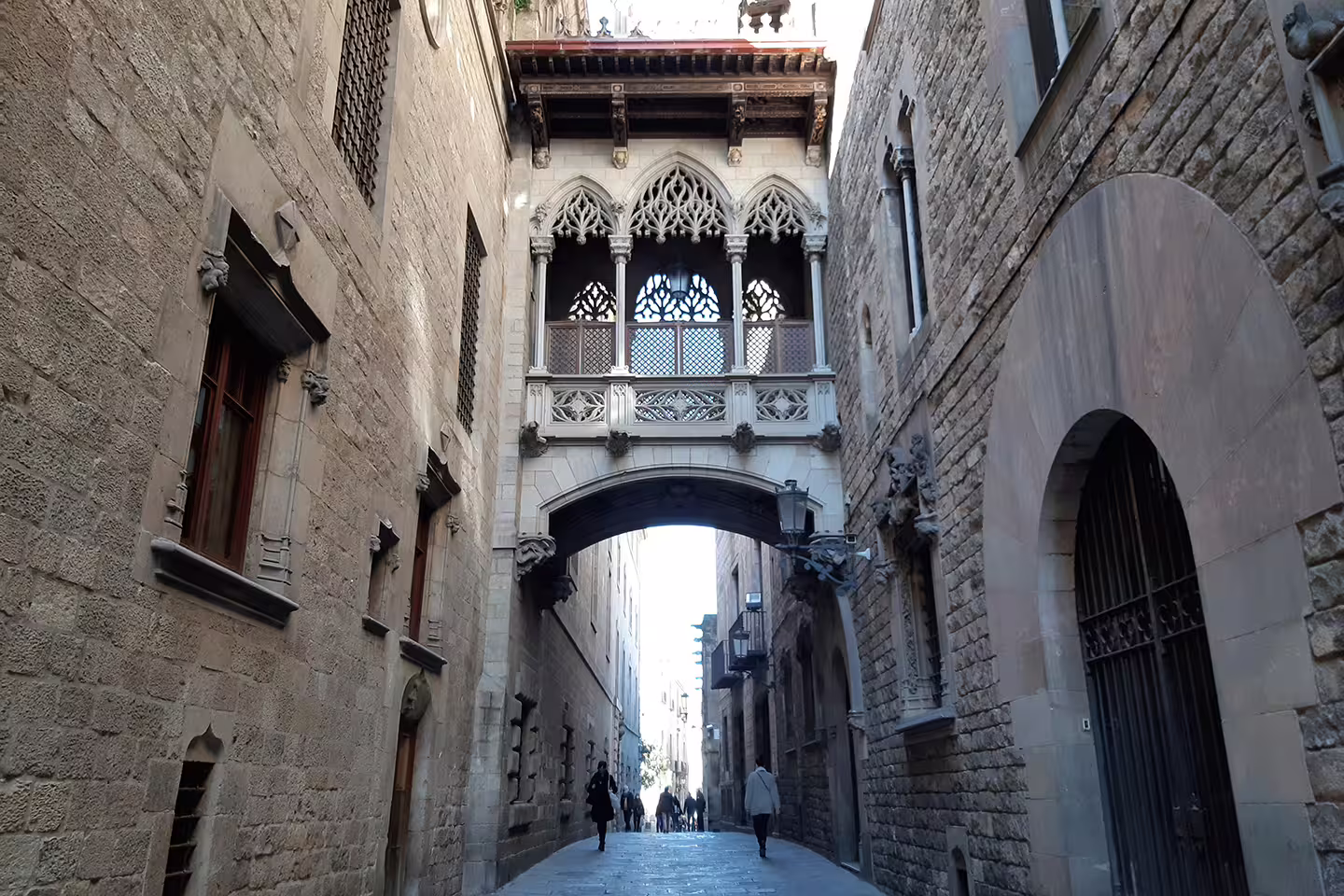 A narrow cobblestone street with a decorative archway in Barcelona's Gothic Quarter.