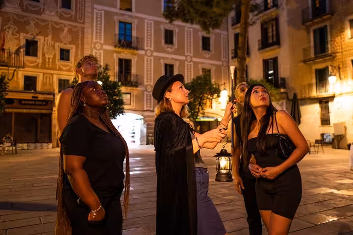Tour group listens to ghostly tales in Barcelona's Gothic Quarter under the evening lights.