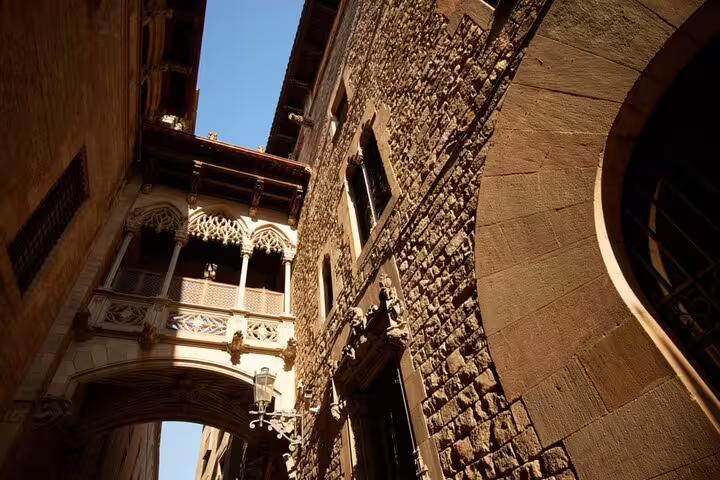 Gothic stone buildings with ornate medieval bridge connecting two structures in Barcelona's Gothic Quarter