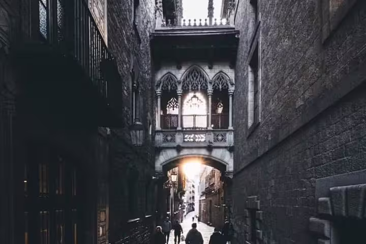 Tourists walk through a historic Gothic Quarter street in Barcelona, highlighting the charm of a small group walking tour.
