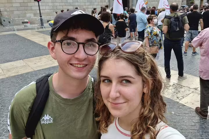 Two young tourists smiling during Barcelona Gothic Quarter walking tour with crowd in background