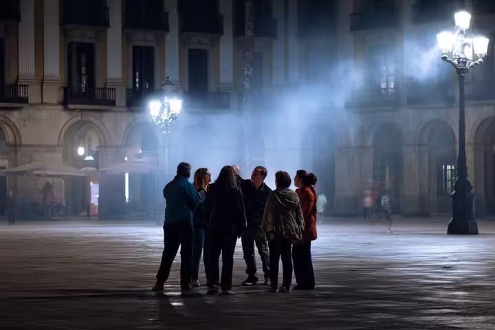 Group of tourists gather under streetlights in Barcelona's eerie square for a Ghosts of a Dark Past walking tour.