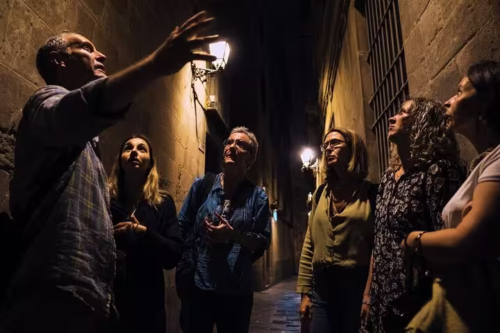 Guide leading a group through a dimly lit alley on the Barcelona Ghosts of a Dark Past Walking Tour.