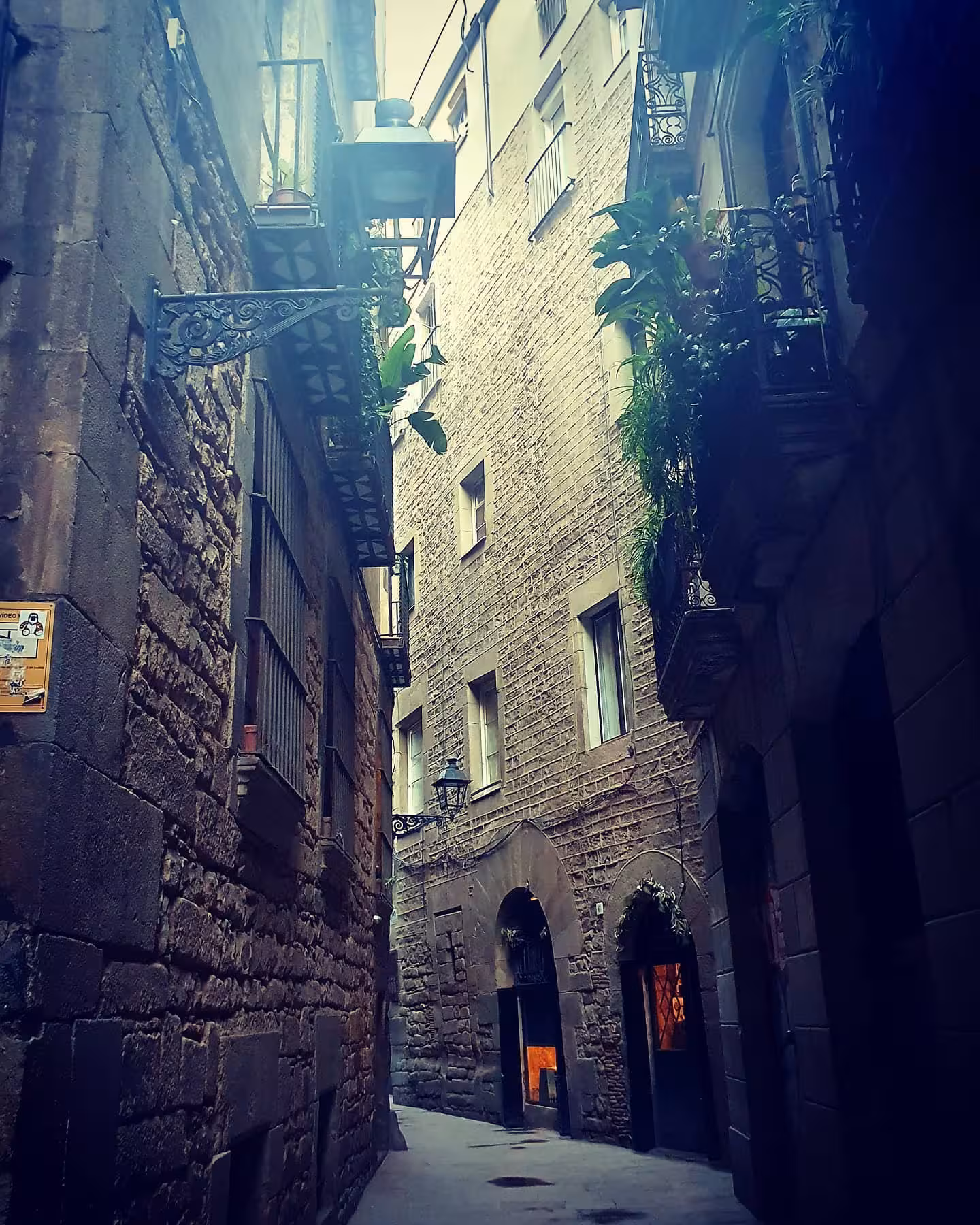 Charming narrow street in Barcelona's Jewish Quarter with stone facades, balconies, and ambient lighting.