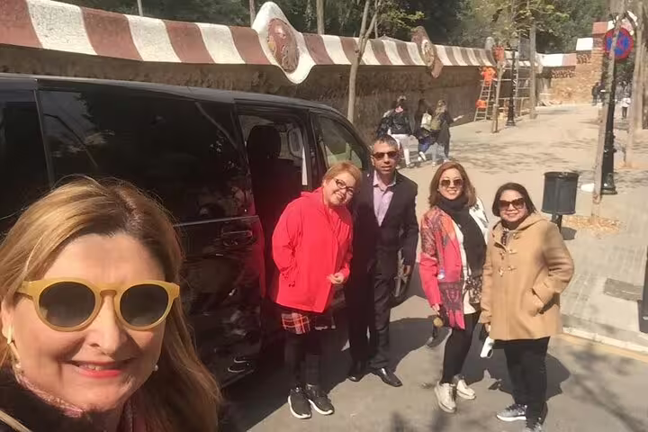 Group of tourists enjoying a sunny day tour in Barcelona with a modern black van in the background.