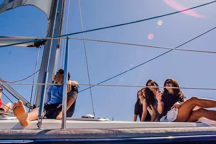Friends relaxing on deck during a Barcelona private luxury sailing tour, sunny Mediterranean sea views