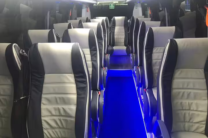 Luxury minibus interior with black and grey leather seats and blue LED floor lighting for private transfer