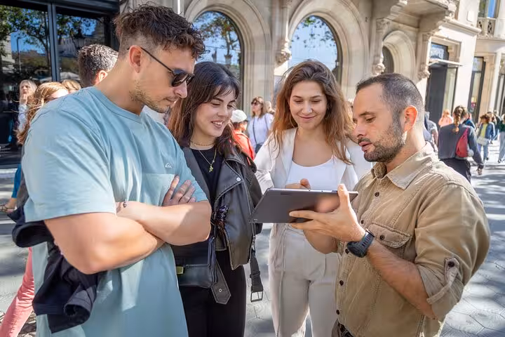 Small group Barcelona Modernist walking tour guide explaining Gaudí landmarks on tablet near Passeig de Gràcia