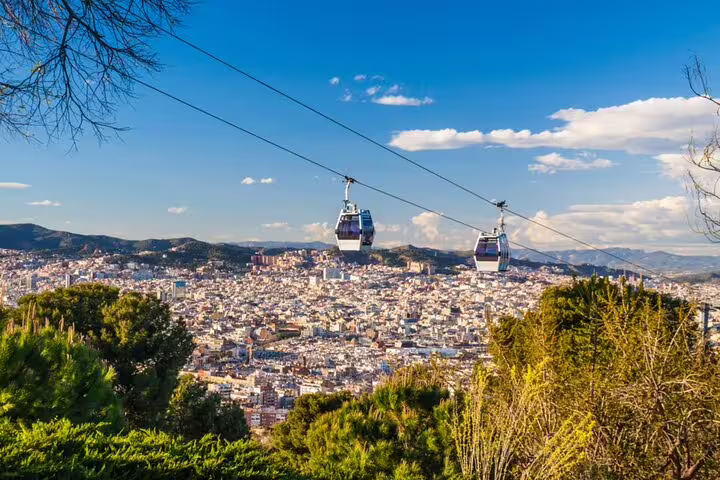 Cable cars over Barcelona cityscape with Montjuic hill and Mediterranean city views under blue sky