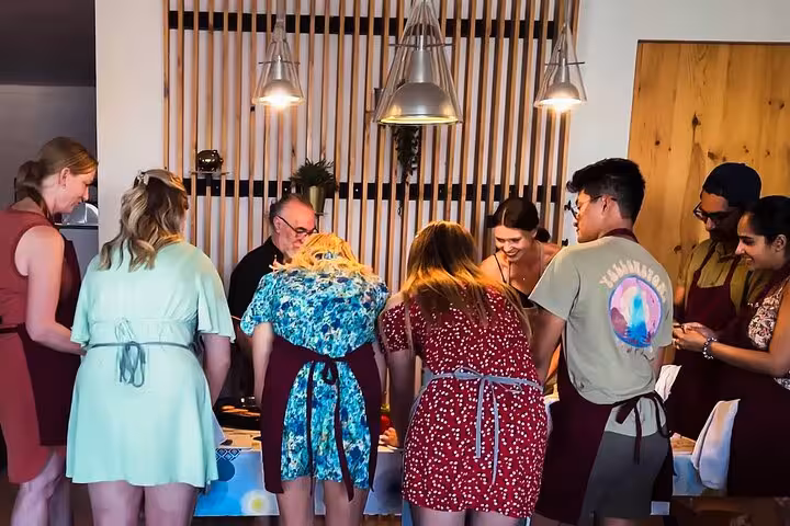 Group of cooking enthusiasts gathered around a table during Barcelona's traditional paella and sangria class.