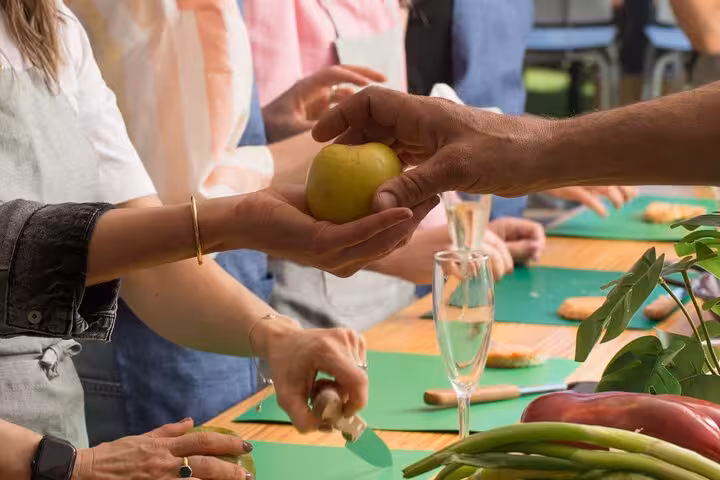 Participants in Barcelona cooking class handling fresh ingredients for authentic paella and sangria preparation.
