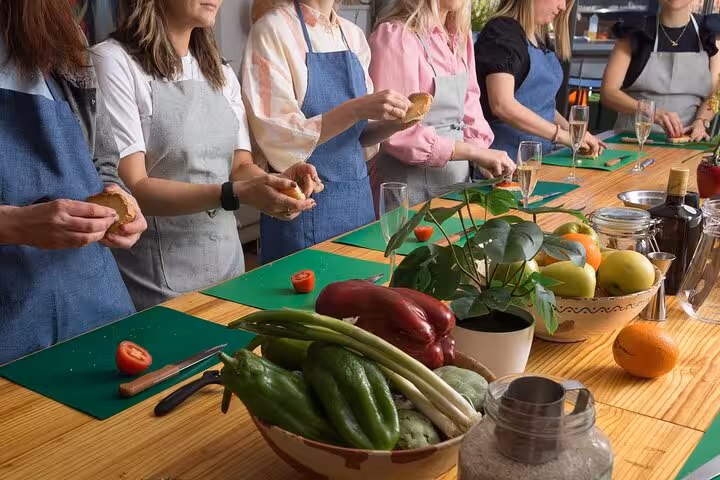 Participants prepare vegetables during a lively Barcelona paella and sangria cooking class, showcasing fresh ingredients.