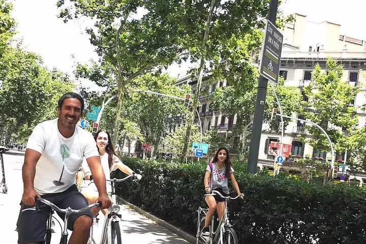 Group enjoying a private bike tour through scenic Barcelona streets, surrounded by lush greenery, with Sagrada Familia tickets included.