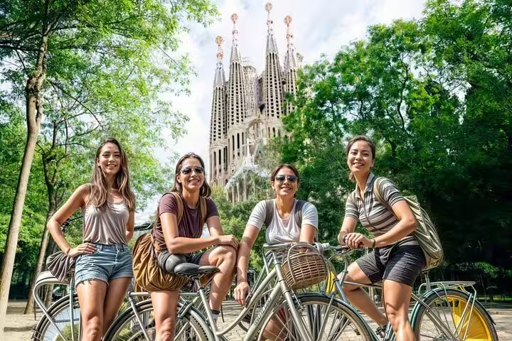 Group of cyclists enjoying a private bike tour in Barcelona with the iconic Sagrada Familia in the background on a sunny day.