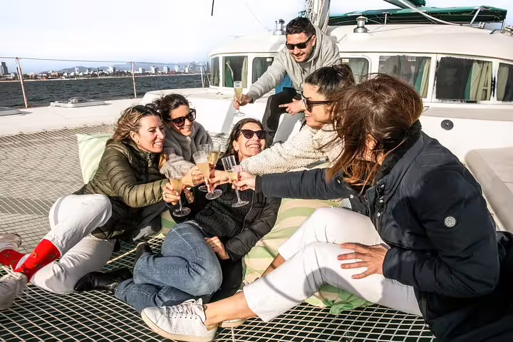 Group enjoying a private Barcelona catamaran tour with snacks and cava, embracing a relaxed and scenic sunset experience.