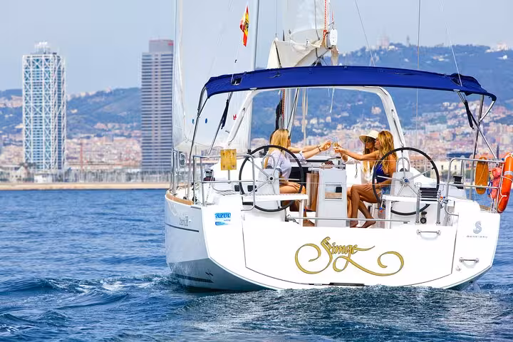 Private sailboat cruising off Barcelona with guests enjoying drinks, open bar, and snacks with skyline views